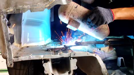 Welding-steel-with-electricity-in-auto-body-repair-shop,-closeup