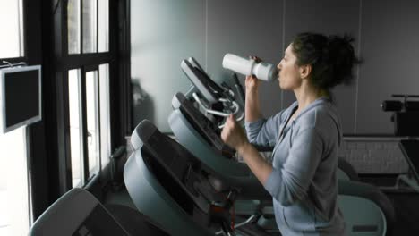 Sportlerin-Trinkwasser-aus-der-Flasche-im-Fitness-Studio