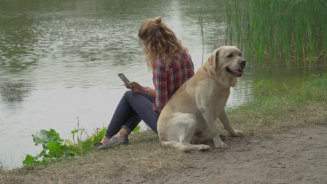 Mujer-joven-y-labrador-está-sentado-espalda-con-espalda