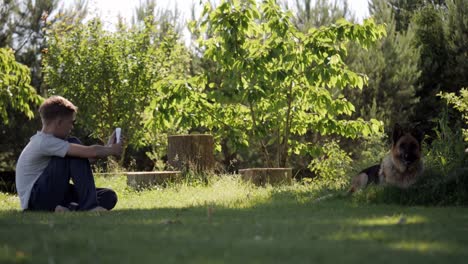 Teenager-unter-Bild-eines-Hundes,-Deutscher-Schäferhund-liegend-Rasen