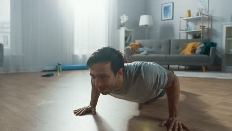 Athletic-Fit-hombre-en-camiseta-y-pantalones-cortos-es-haciendo-Push-Up-ejercicios-en-casa-en-su-amplio-y-luminoso-apartamento-con-Interior-minimalista.