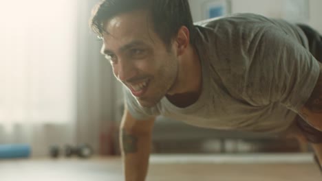 Movimiento-Slow-Close-Up-de-un-hombre-cabe-en-camiseta-y-pantalones-cortos-es-haciendo-montaña-escaladores-mientras-utiliza-un-cronómetro-en-su-teléfono.-Que-está-entrenando-en-su-casa-en-su-apartamento-con-Interior-minimalista.