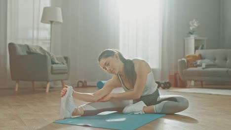 Hermosa-chica-de-Fitness-confía-en-una-ropa-de-entrenamiento-atlético-es-hacer-estiramientos-ejercicios-de-Yoga-en-su-brillante-y-amplia-sala-de-estar-con-Interior-moderno-acogedor.