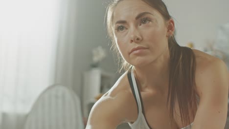 Close-Up-of-a-Beautiful-Confident-Fitness-Girl-in-an-Athletic-Workout-Clothes-Doing-Stretching-Yoga-Exercises-in-Her-Bright-and-Spacious-Living-Room-with-Cozy-Minimalistic-Interior.