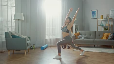 Beautiful-Confident-Busty-Fitness-Girl-in-an-Athletic-Top-is-Doing-Stretching-Yoga-Exercises-in-Her-Bright-and-Spacious-Apartment-with-Minimalistic-Interior.