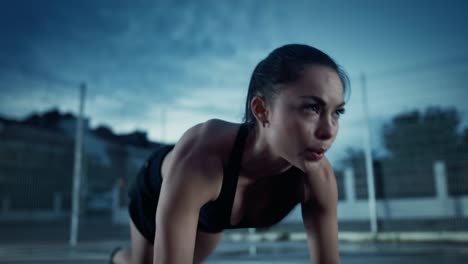 Ejercicios-de-escalador-energético-Fitness-chica-haciendo-montaña-hermosa.-Ella-está-haciendo-un-entrenamiento-en-una-cancha-de-baloncesto-al-aire-libre-cercado.-Imágenes-de-noche-después-de-la-lluvia-en-una-zona-de-barrio-residencial.