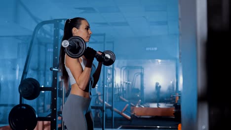 Beautiful-girl-makes-exercise-for-biceps.-W-shaped-bar.-Dark,-smoke,-gym.-Close-up