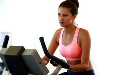 Fit-brunette-de-trabajo-en-la-bicicleta-de-ejercicio