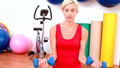 Blonde-Frau-heben-Kurzhanteln-auf-Gymnastikball