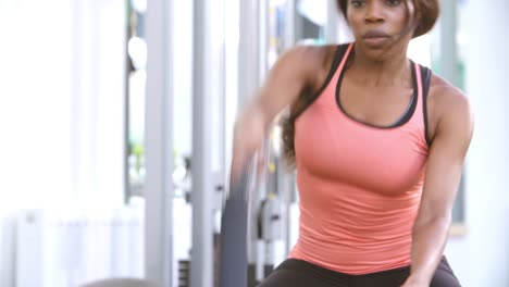 Mujer-joven-haciendo-ejercicios-con-batalla-cuerdas-en-un-gimnasio