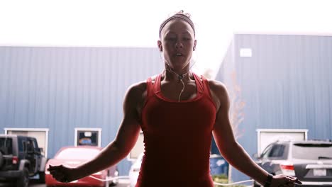 A-fit-young-woman-jumping-rope-outside-of-a-small-gym-while-listening-to-music