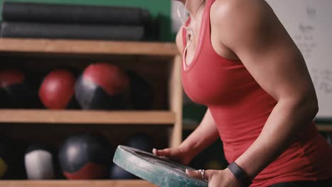 Un-ajuste-mujer-joven-haciendo-ejercicios-con-un-tope-placa-en-un-pequeño-gimnasio-mientras-escuchando-música