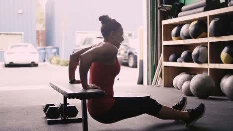 A-fit-young-woman-working-out-with-a-bumper-plate-in-a-small-gym-while-listening-to-music