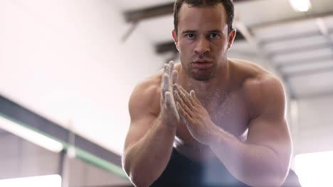 A-fit-young-man-chalking-up-at-the-gym-and-staring-into-the-camera