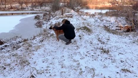 Mann-trainiert-den-Hund-in-der-Nähe-von-Teich-im-Winter