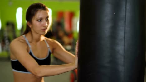 Young-boxer-man-practicing-on-a-punching-bag-with-woman-help