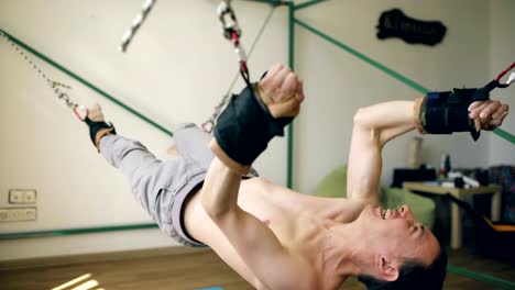 Young-man-doing-exircise-on-quartering-fitness-equipment-and-pull-his-arms-and-legs-with-ropes