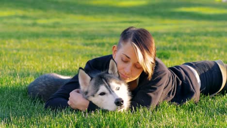 Schöne-junge-Frau,-die-das-Spiel-mit-lustigen-husky-Hund-draußen-im-park