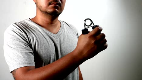 man-do-exercises-workout--with-squeezes-hand-grip-for-hand,-fingers,-muscles-on-white-wall-background.