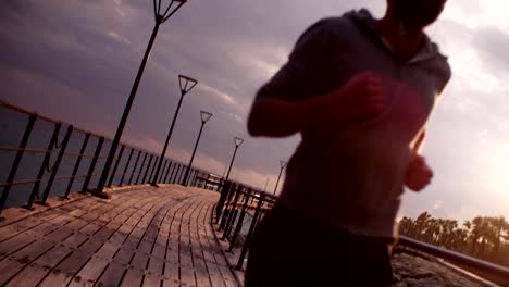 Young-fit-man-running-and-listening-to-music-at-sunset