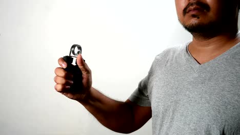 man-do-exercises-workout--with-squeezes-hand-grip-for-hand-muscles-on-white-wall-background.