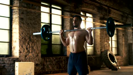 Hombre-sin-camisa-atlética-fuerte-ascensores-con-barras-pesadas-como-parte-de-la-rutina-de-entrenamiento-de-Fitness.-Gimnasio-es-en-fábrica-remodelada.