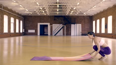 Young-woman-unfolds-a-yoga-mat