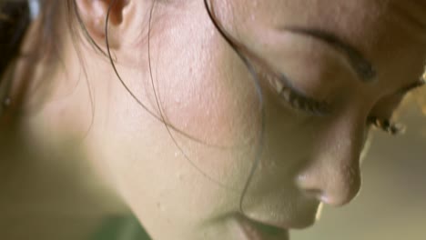 Close-up-Shot-of-a-Beautiful-Athletic-Woman-Wipes-Sweat-from-Her-Forehead-with-a-Hand,-Looks-into-Camera.-She's-Tired-after-Intensive-Cross-Fitness-Exercise.