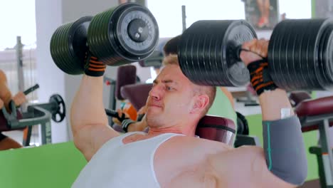 Sportlicher-junger-Mann-Aufhebung-Hanteln-im-Fitnessstudio