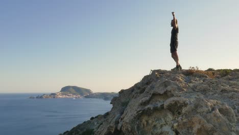 Runner-exulting-on-top-of-a-cliff-on-an-island-in-front-of-the-ocean