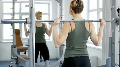 Young-woman-makes-squats-with-barbell-in-the-gym