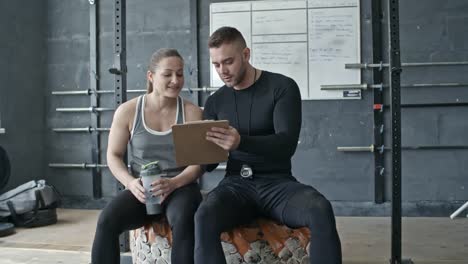 Cross-Training-Coach-im-Gespräch-mit-sportlichen-Frau-im-Fitness-Studio