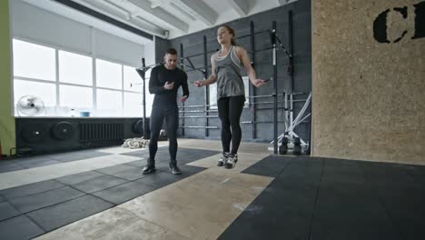 Woman-Doing-Jumping-Rope-Exercise-with-Coach-in-Gym