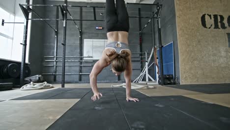 Muskulöse-Frau-zu-Fuß-auf-Händen-in-Cross-Training-Fitness-Studio