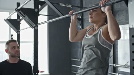 Strong-Woman-Doing-Chin-Up-Exercise-with-Coach