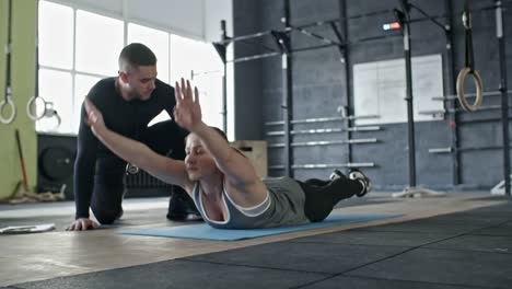 Woman-Doing-Back-Extension-Exercise-with-Help-of-Coach