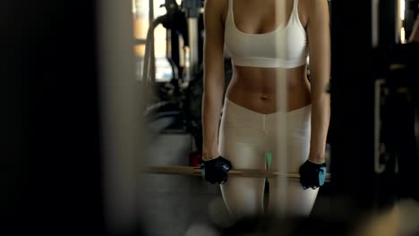 Sexy-woman-making-incline-with-barbell-and-looking-in-mirror-on-gym-club