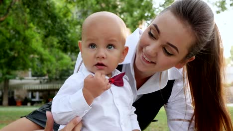 Porträt-von-kleiner-Gentleman-mit-Mama-auf-grünen-Rasen-im-Park-sitzen