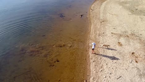 Woman-with-her-pet-dog-standing-near-river-coast-on-a-sunny-day-4k