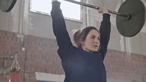 Gritty-Young-Woman-Raising-Barbell-Overhead