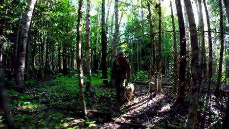 Hunter-with-dog-walking-through-forest-4k