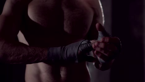 Male-boxer-wraps-his-hands-with-handwrap.-professional-boxer-wrapping-bandages-on-his-hand.-Fighter-wrapping-hands-with-boxing-wraps-in-the-gym