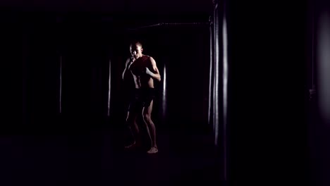 Kickboxer-shadow-boxing-as-exercise-for-the-fight.-Fighter-training-punching.-Boxing-in-the-darknes.-Young-boxer-training-in-the-gym