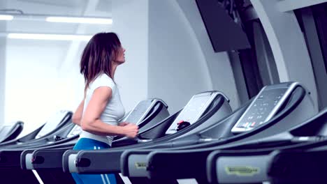 Adult-woman-runs-on-treadmill-at-the-fitness-centre.-Attractive-sporty-girl-running-on-the-treadmil