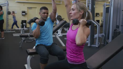 Levantamiento-de-pesas-con-instructor-en-el-gimnasio-de-mujer