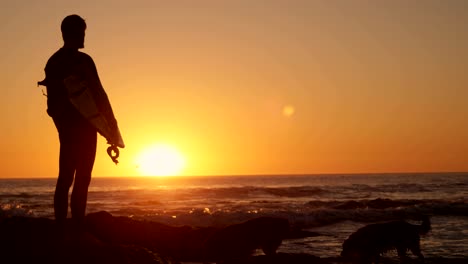 Man-standing-with-surfboard-in-the-beach-4k