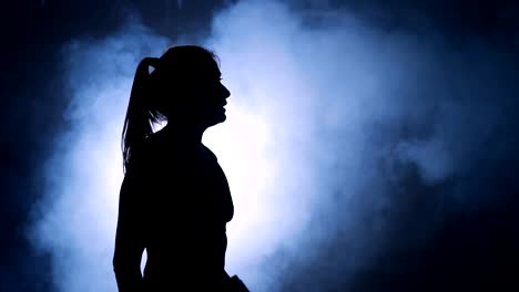 Fitness-healthy-woman-tired-after-strength-training-exercise-at-gym.-Female-boxer-resting.-Silhouette-in-a-smoky-gym