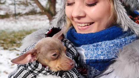 Frau-spielt-mit-ihren-kleinen-Hund-draußen-winter