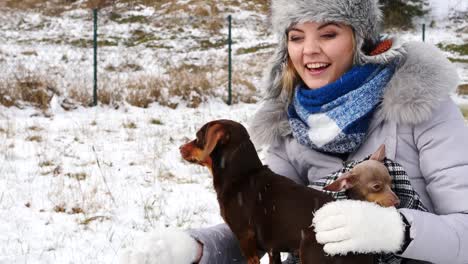 Frau-spielt-mit-ihren-kleinen-Hunden-draußen-winter