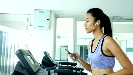 Woman-listen-song-while-exercise.-Asian-woman-Exercise-at-gym.-Sport-and-Reaction-concept.-4k-Resolution.